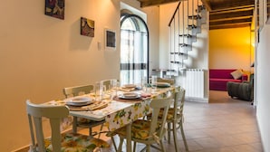 A dining area with a table set for four, chairs, and a staircase leading to another room.