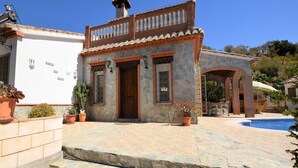 A stone building with a wooden door and windows, a pool, and potted plants. - Villa Mariposa in Spain's Sunny Paradise (Arenas)