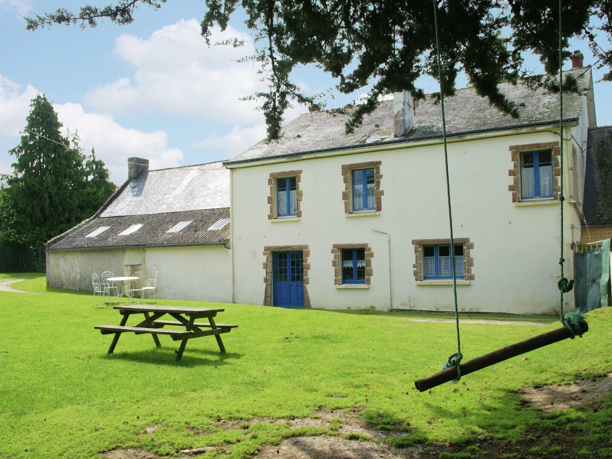 A building with a picnic table and swing set in a grassy area.