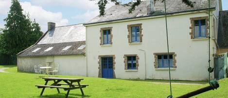 A building with a picnic table and swing set in a grassy area.