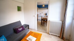 A living room with a sofa, a coffee table, and a view into a kitchen area. - Wildlife Haven Near Le Pouldu (Clohars-Carnoet)