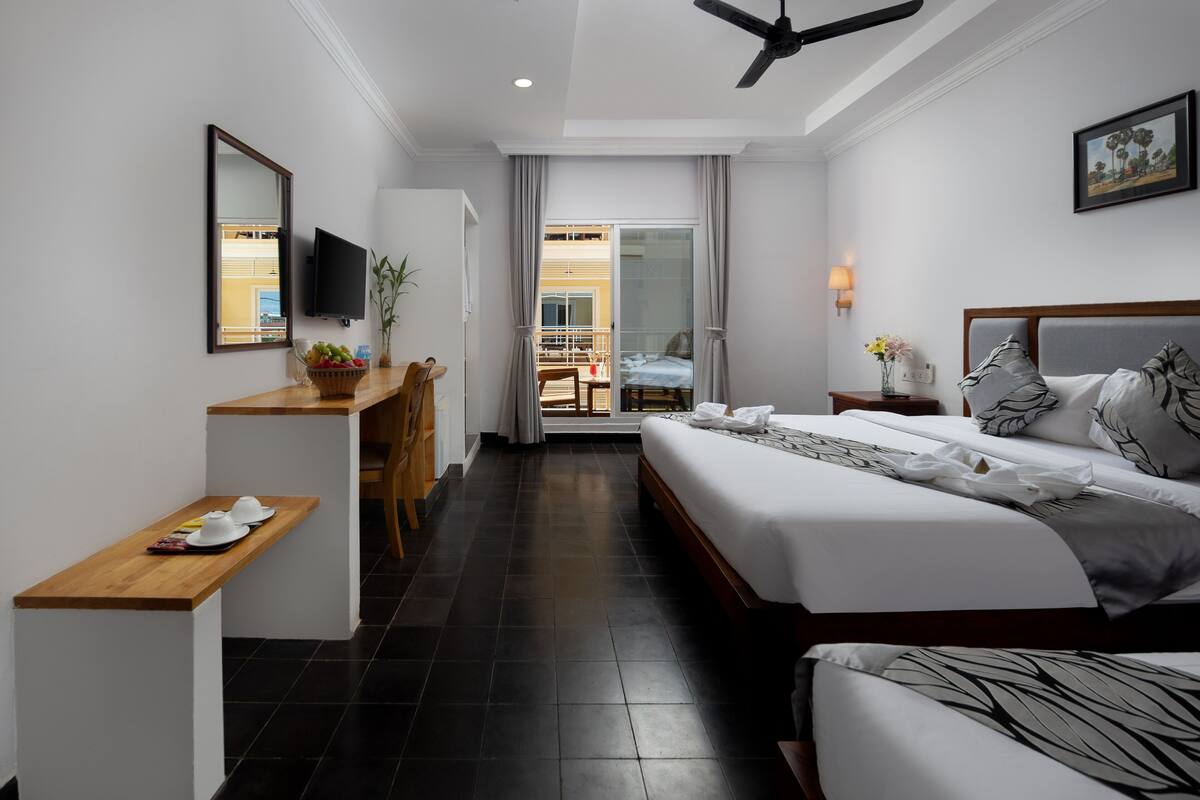 A hotel room with a bed, a desk, a television, and a balcony with a view.