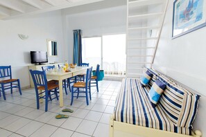 A room with a bed, a dining table with chairs, a television, and a window with curtains. - Apartment in France with Ocean View (Fouras)
