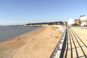 A beach with a walkway, people walking, and buildings in the background. - Apartment in France with Ocean View (Fouras)