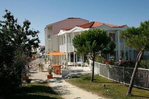 A building with a red-tiled roof, a covered outdoor seating area with orange umbrellas, and a white fence surrounding the property.