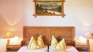 Ein Doppelbett mit Holz-Kopfteil, zwei Nachttische mit Lampen sowie ein Landschaftsbild an der Wand.