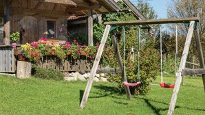 Ein Holzhaus mit Veranda, Schaukel und einem blühenden Garten.