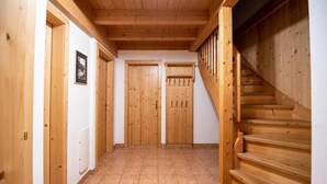 A hallway with wooden doors, a tiled floor, and a wooden staircase.