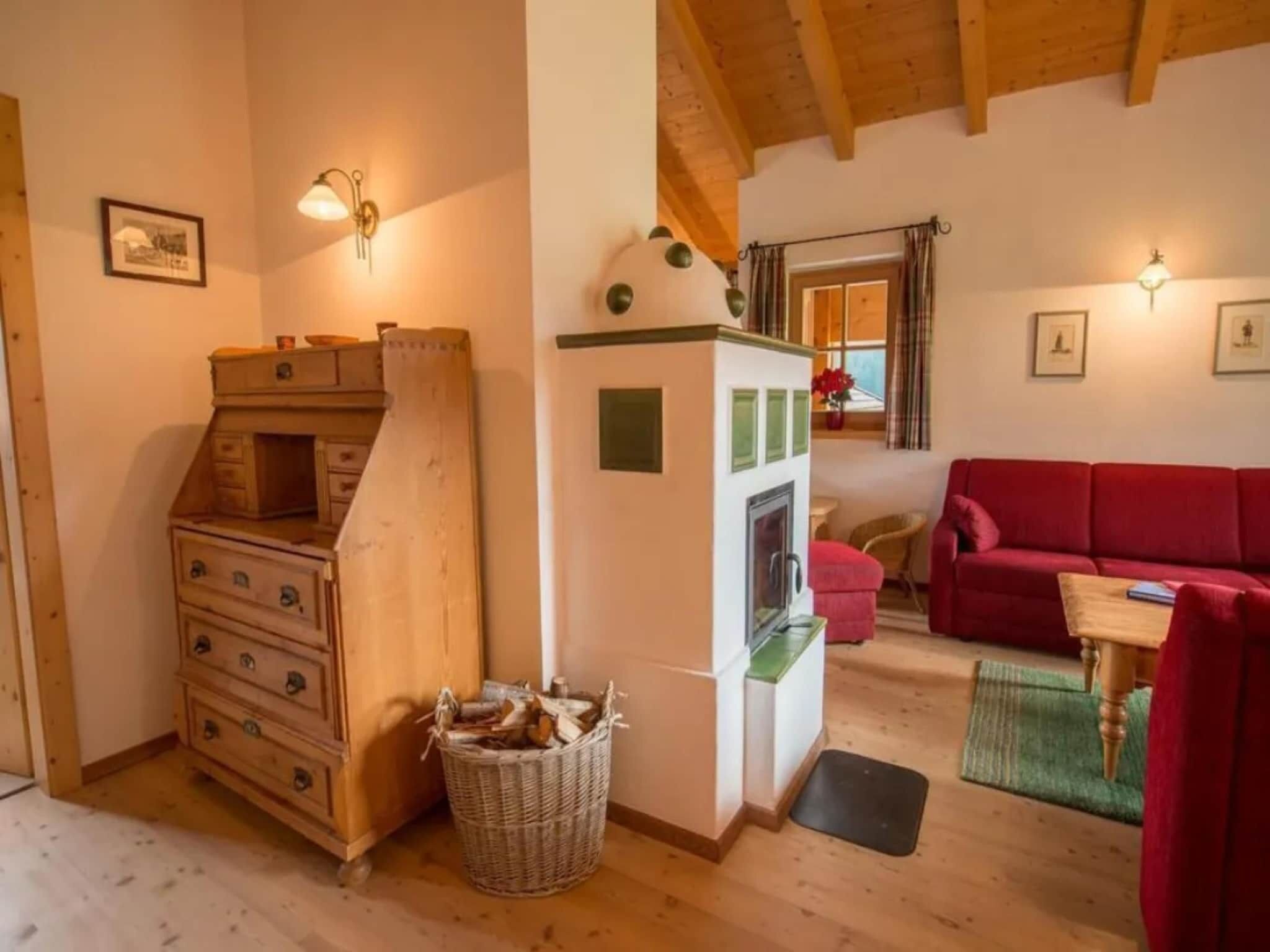 Ein gemütliches Wohnzimmer mit einem roten Sofa, Holzschränken, einem Kamin und einem Essbereich mit Tisch und Stühlen.