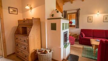 Ein gemütliches Wohnzimmer mit einem roten Sofa, Holzschränken, einem Kamin und einem Essbereich mit Tisch und Stühlen.