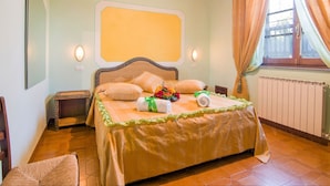 A bedroom with a bed, two bedside tables, a mirror, and a window with curtains. - Belvilla by OYO Large Farmhouse with Pool (Castiglione del Lago)