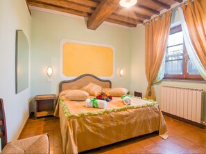 Cozy retreat with a large bed, wooden ceiling, and a window with curtains.
