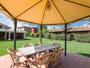 Relax in the shaded patio area, surrounded by lush greenery and a beautifully maintained lawn.