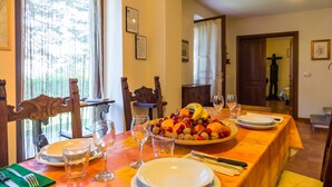 Una mesa de comedor dispuesta con platos, vasos y una bandeja de frutas.