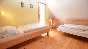 A room with two wooden beds, a small table, and a chair. - Holiday Home in Forest with Private Pool (Petrohrad)