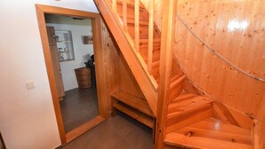 A wooden staircase leading to a second floor, with a kitchen visible in the background. - Holiday Home in Forest with Private Pool (Petrohrad)