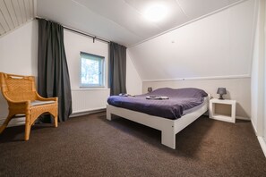A bedroom with a bed, a chair, a nightstand, and a window. - Farmhouse in Dalfsen near Forest Trails (Dalfsen)