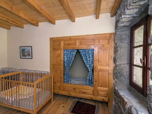 Une pièce chaleureuse avec un berceau en bois, un mur en pierre et une fenêtre avec un rideau.