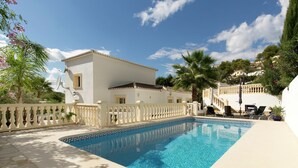 A swimming pool with a white fence, a white building with a balcony, and palm trees. - Sunny Coastal Stay in Zingst (Moraira)