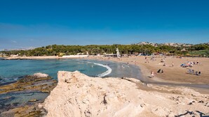 A beach with clear blue water, sandy shore, and a rocky outcrop in the foreground. - Sunny Coastal Stay in Zingst (Moraira)