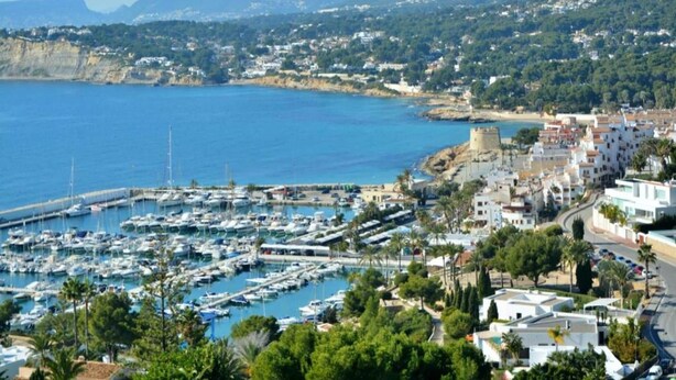 A coastal marina with boats, a historic tower, and a town with buildings and greenery. - Sunny Coastal Stay in Zingst (Moraira)