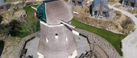 A modern building with a unique conical roof, surrounded by smaller houses with similar architectural styles.