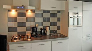 A modern kitchen with a gas stove, coffee maker, and built-in oven. - Holiday Home in Egmond near the Beach (Egmond aan zee)