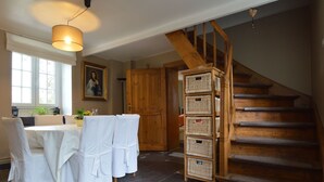 A dining area with a table set for four, a wooden staircase, and wicker baskets.