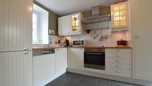 A kitchen with white cabinetry, a microwave, an oven, and a window.