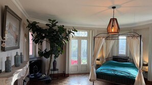 A bedroom with a canopy bed, a fireplace, a large plant, and a view through a glass door. - Luxury Estate with Pool & Spa (Jamoigne)