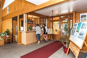 A wooden interior with a reception desk, a red carpet, and informational posters. - Chalet Apartment by Lake Geneva, Evian (Bernex)