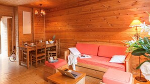 A cozy wooden cabin interior with a dining area, a sofa, and a laptop on a table. - Chalet Apartment by Lake Geneva, Evian (Bernex)