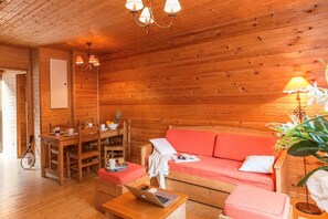 Ein gemütliches Holzblockhaus-Interieur mit Essbereich, einer Couch und einem Laptop auf einem Tisch.