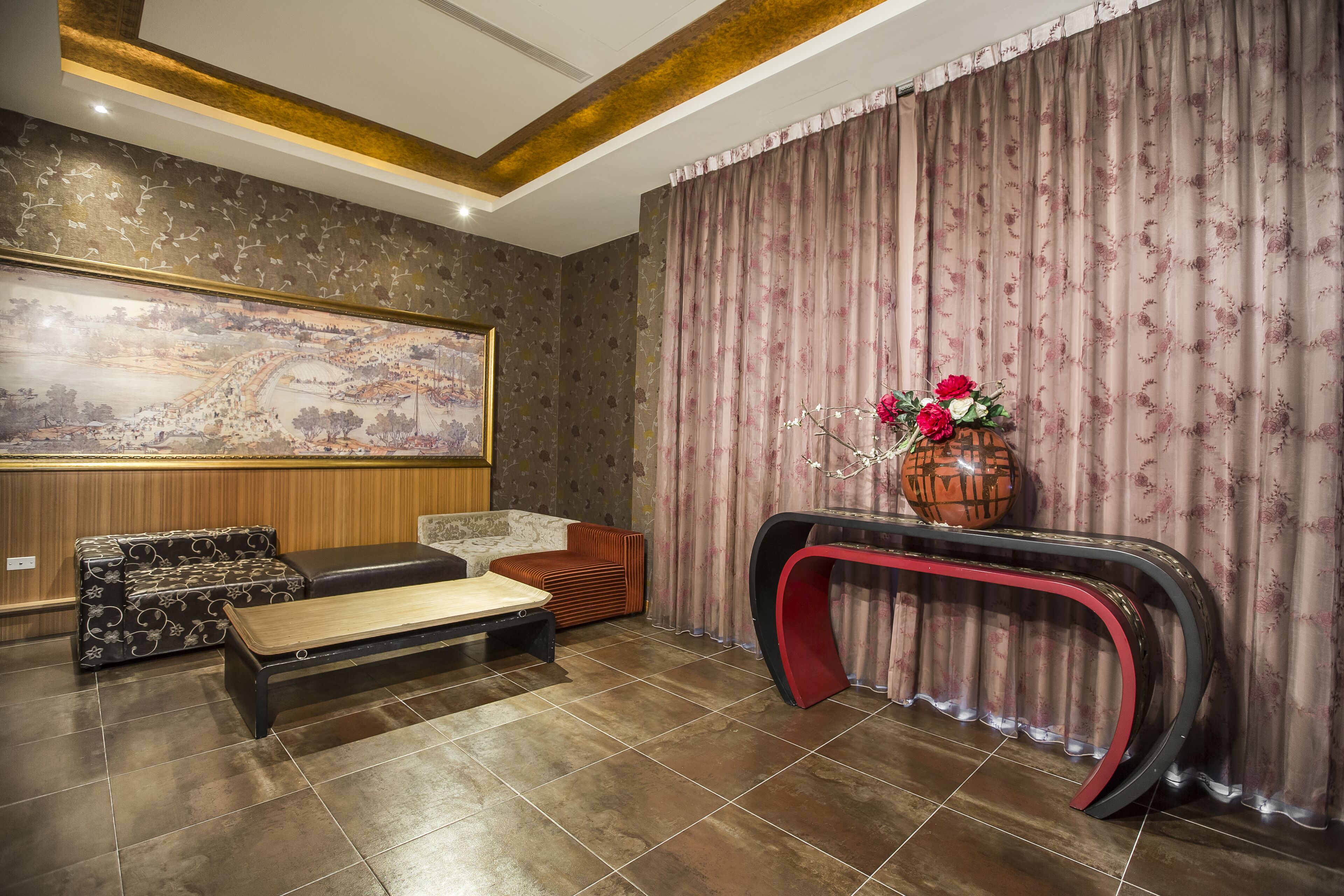 A modern living room with a large abstract painting, a sofa set, a coffee table, and a console table with a vase of flowers.
