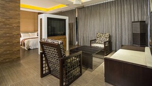 Een moderne hotelkamer met een bed, een televisie, een bank en een bureau.