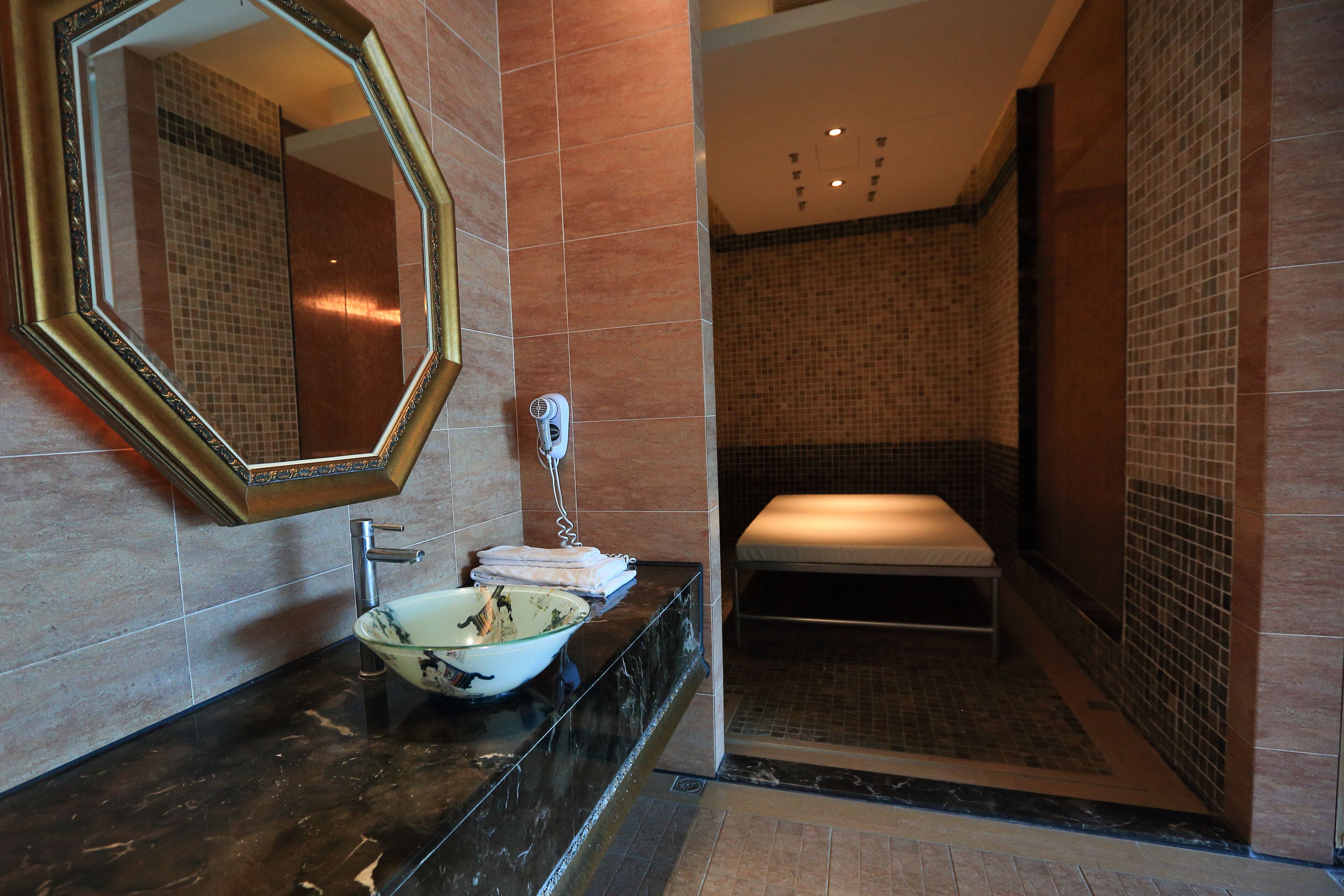 A bathroom with a marble sink, a large mirror, and a shower area.
