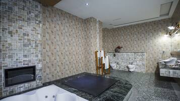 A modern bathroom with a large bathtub, a shower area, and a toilet.