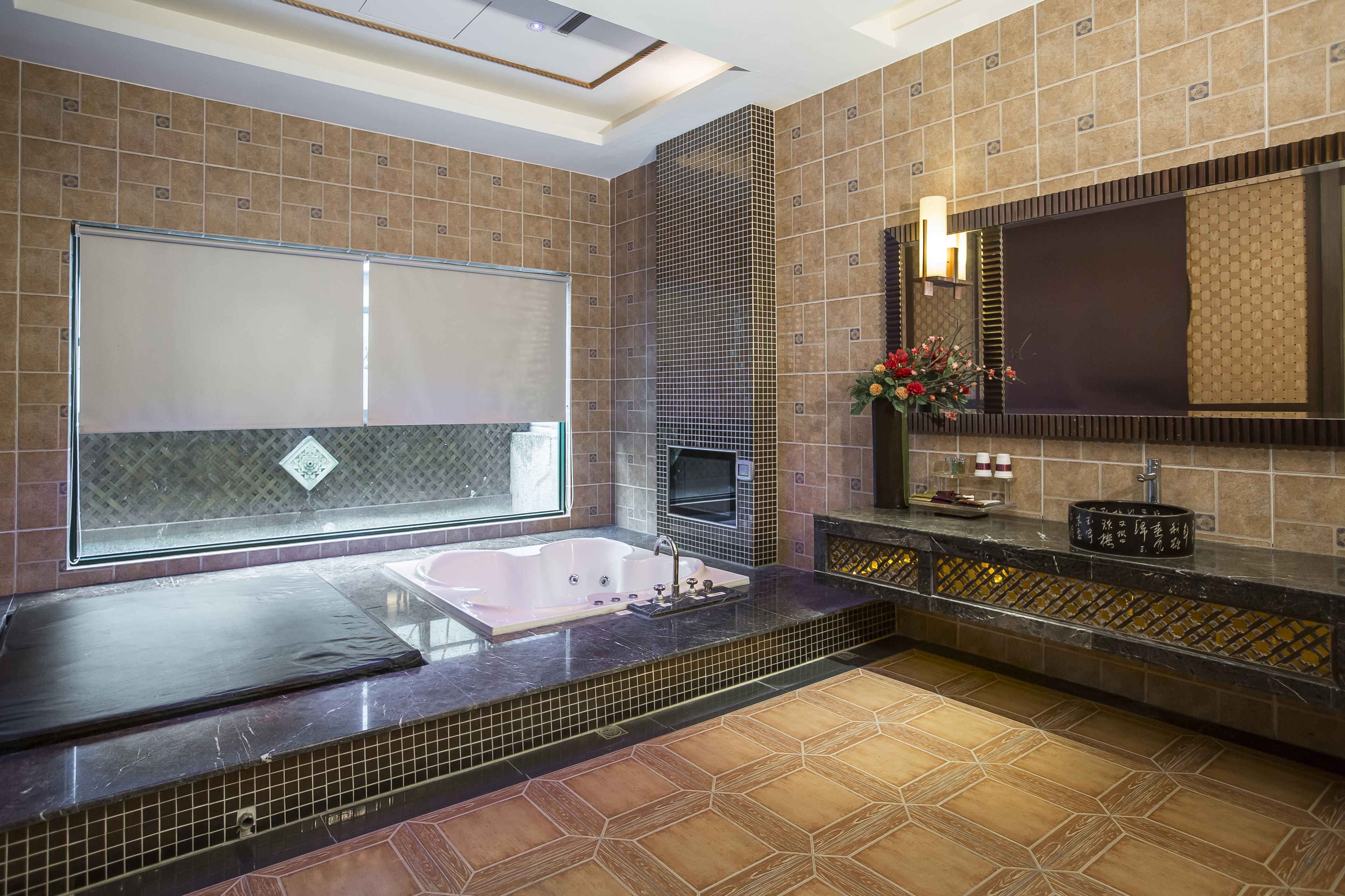 Une salle de bain moderne avec une grande baignoire, un miroir et un sol carrelé.