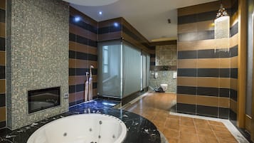 Un baño moderno con una bañera grande, cabina de ducha de vidrio y una lámpara colgante decorativa.
