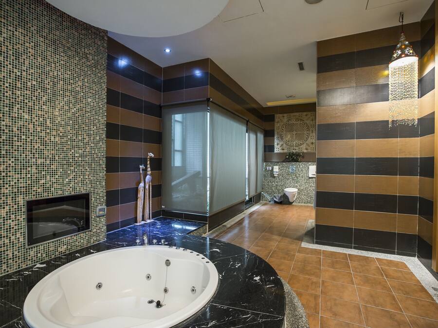 Un baño moderno con una bañera grande, cabina de ducha de vidrio y una lámpara colgante decorativa.