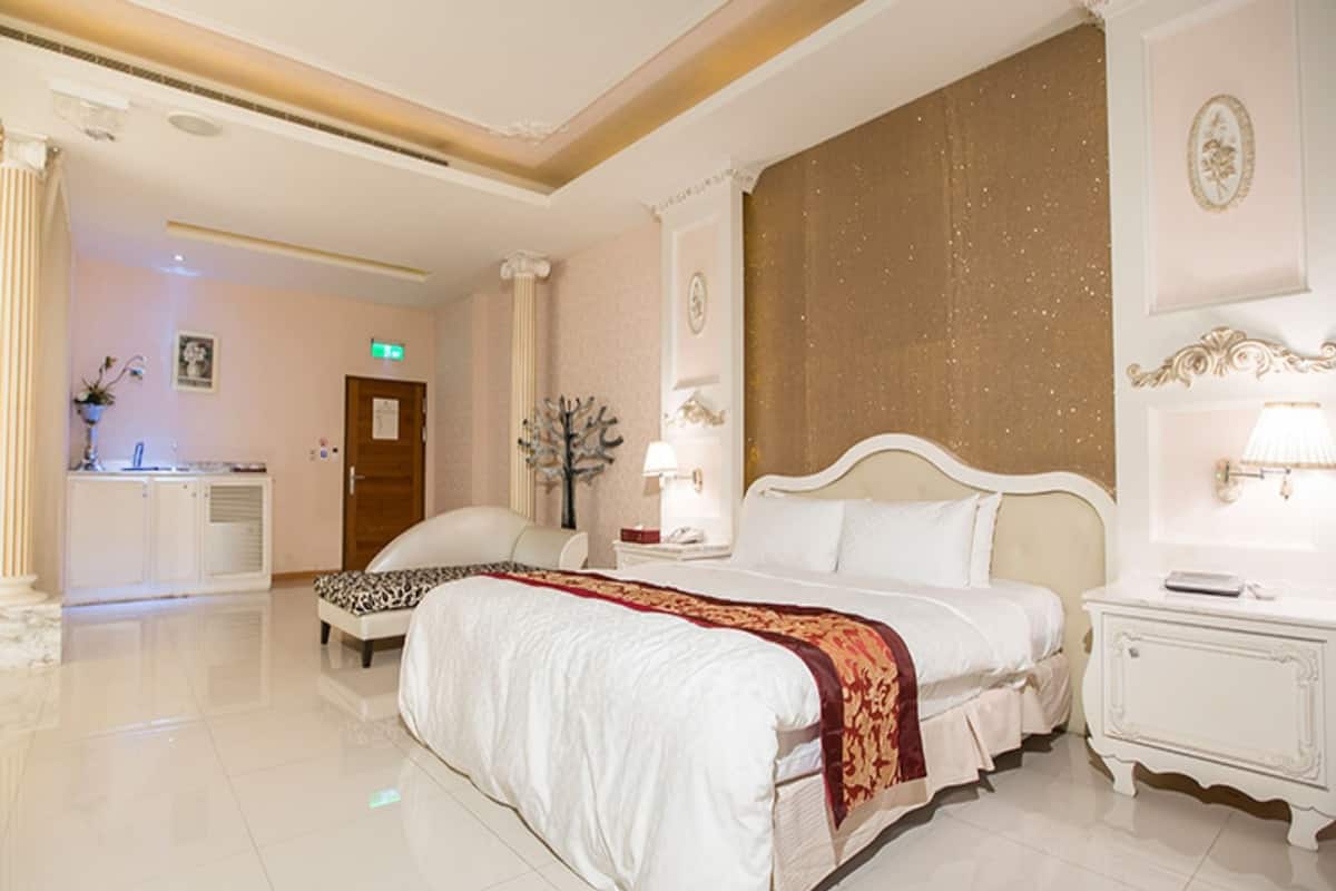 Hotelkamer met een groot bed, nachtkastje, bureau en stoel.