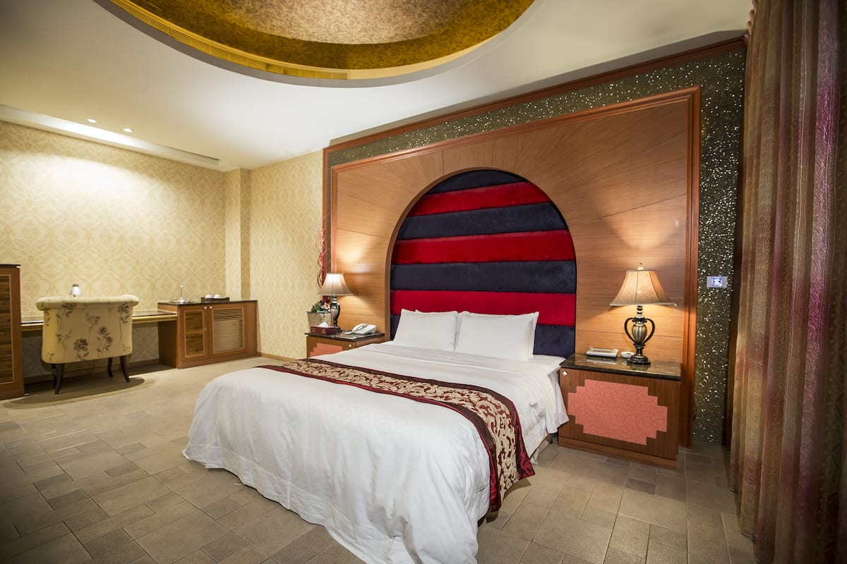 Een hotelkamer met een groot bed, een bureau en twee bedlampjes.