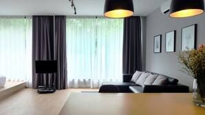 A modern living room with a flat-screen TV, a dining table, and a sofa. - Srianunt Boutique Hotel (Buriram)