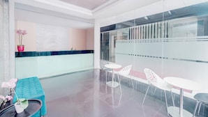 Zona d'entrada moderna amb un separador de vidre, taulell de recepció i espais d'espera.