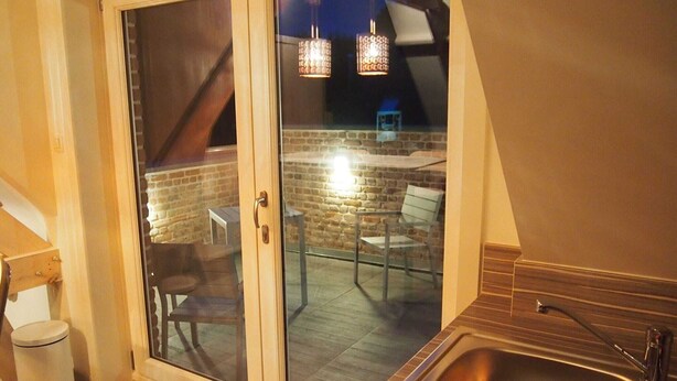 A modern bathroom with a glass door leading to an outdoor patio area.
