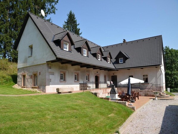 A two-story house with a stone facade, multiple windows, and a covered patio area.