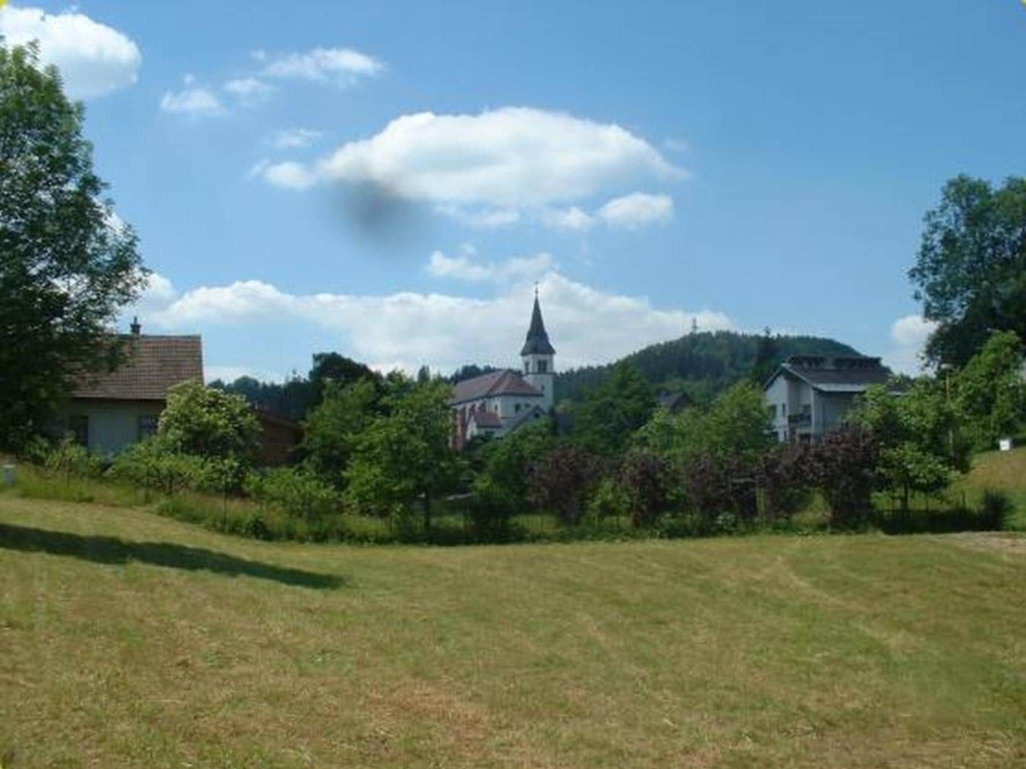 A rural landscape with a church, houses, and a grassy field.