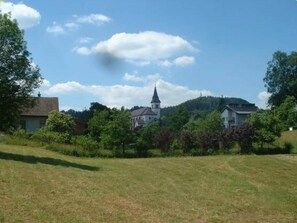 A rural landscape with a church, houses, and a grassy field.