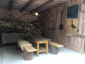 A rustic wooden interior with a wooden table, benches, and a painting on the wall.