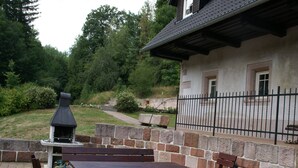 Un patio al aire libre con paredes de piedra, una parrilla y bancos de madera.